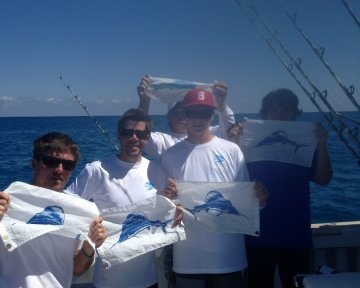 people on a boat holding blue marlin flags